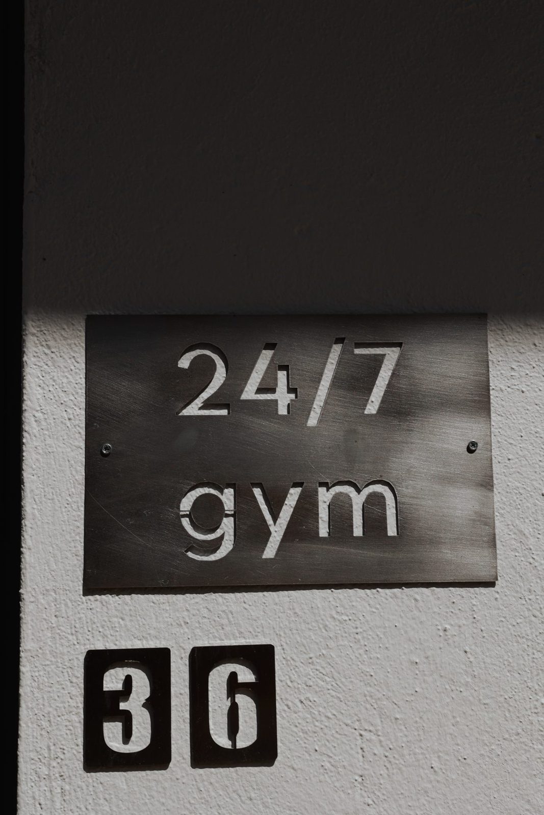 Metal sign on the wall reading 24/7 gym, number 36