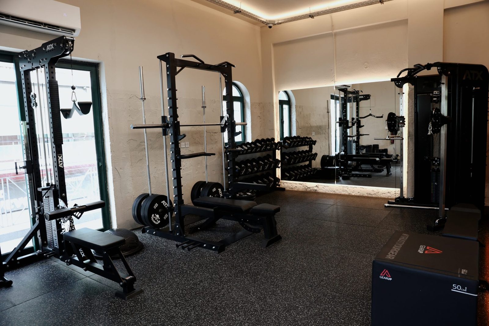 The Reason gym floor with racks, benches and a mirror wall under warm cove lighting