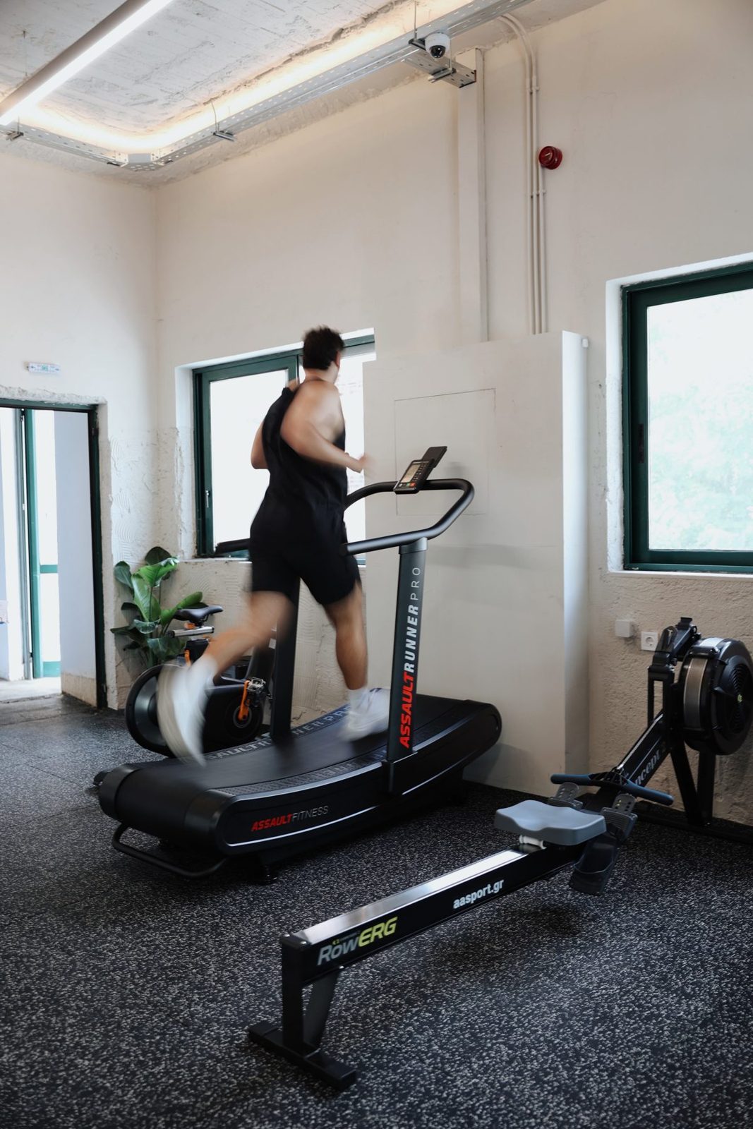 A treadmill and a rowing machine by the window in the bright gym